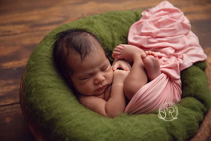 Newborn girl in pink in a bowl